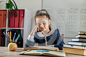 cute industrious child is sitting at a table indoors.