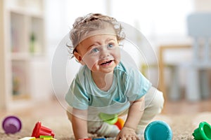 Cute infant baby crawling on the floor at home, playing with colorful toys photo