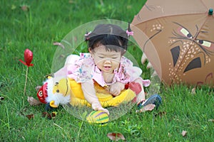 Cute innocent baby girl play plush toy and ball on the lawn