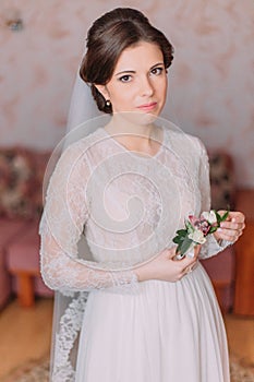 Cute innocent bride at home in white wedding dress, preparations concept. Portrait of tender girl in gown