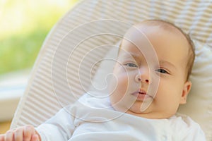Cute innocent little newborn awake in a hammock. The child looks around. Mode for newborn time outdoors. Child sleep on