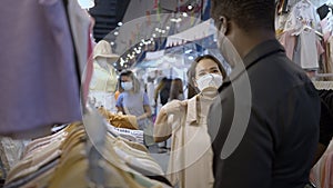 Cute interracial couple shopping together. Girl shows blouse to boy and he dislikes it - slow motion shot