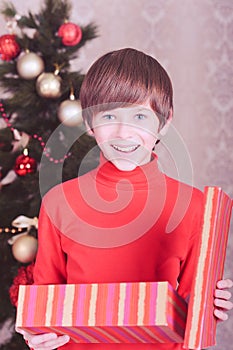 Cute kid boy open christmas present in room