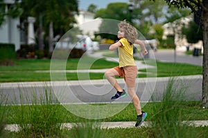 Cute kid boy running across american neighborhood street. Summer, childhood, leisure and people concept. Happy little