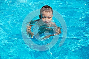Cute kid, boy swimming in pool water
