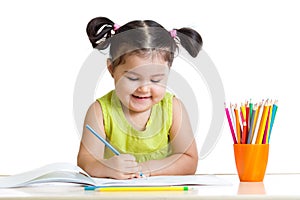 Cute kid drawing with colorful pencils and smiling