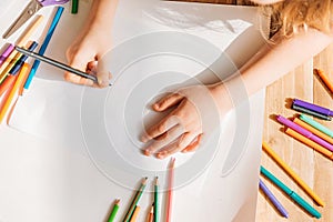 Cute kid drawing on paper with pencils while lying on floor