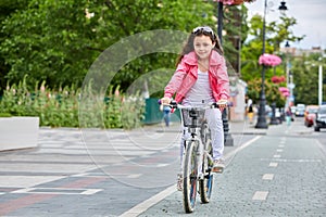 Cute kid girl in blue helmet going to ride her bike