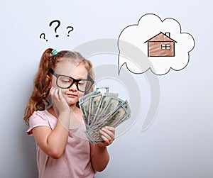 Cute kid girl in eyeglasses looking on money and thinking how sp