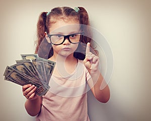 Cute kid girl holding dollars and have an idea how earning much