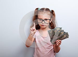 Cute kid girl holding dollars and have an idea how earning much