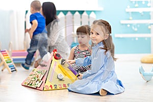 Cute kid girl playing with busyboard. Children`s educational toys.