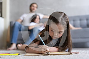 Cute kid girl playing on floor, preschool little girl drawing with colored pencils on paper spending time with family