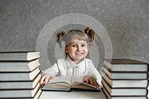 Cute kid girl preschooler with glasses, with books at home