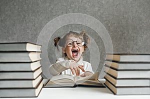 Cute kid girl preschooler with glasses, with books at home