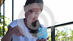 Cute kid girl putting coins into piggy bank outdoors