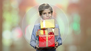 Cute kid holding stack of gift boxes.