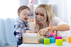 Cute kid and mother playing with toys at home. Little boy having fun pastime in nursery.