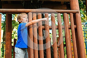 Cute kid playing in tree house on backyard. Happy childhood. Summer holidays concept. Tree house for kids. Happy boy plays in an