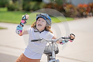 Cute kid riding a bike in summer park. Children learning to drive a bicycle on a driveway outside. Kid riding bikes in