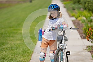 Cute kid riding a bike in summer park. Children learning to drive a bicycle on a driveway outside. Kid riding bikes in