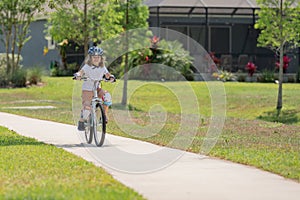 Cute kid riding a bike in summer park. Children learning to drive a bicycle on a driveway outside. Kid riding bikes in