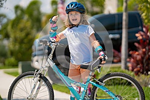 Cute kid riding a bike in summer park. Children learning to drive a bicycle on a driveway outside. Kid riding bikes in