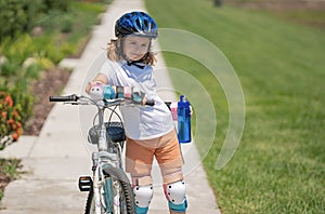 Cute kid riding a bike in summer park. Children learning to drive a bicycle on a driveway outside. Kid riding bikes in