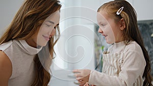 Cute kid touching mother face kitchen portrait. Laughing mom bonding to daughter