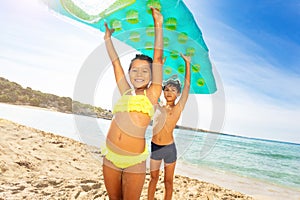 Cute kids with air mattress overhead on the beach