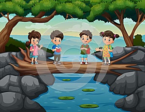 Cute kids cross the river on the tree trunk bridge