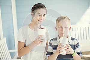 Cute kids drinking milkshakes or flavored drinks together