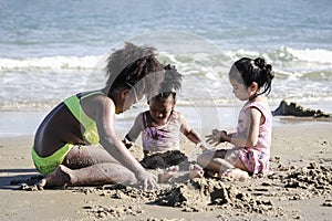 Cute kids having fun on sandy summer with blue sea, happy sister making sand castle, playing with sandat on tropical beach