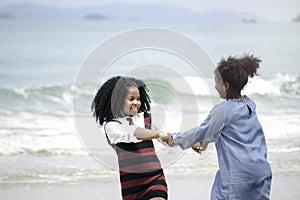 Cute kids having fun together on sandy summer beach with blue sea, happy childhood girls friend playing on tropical beach
