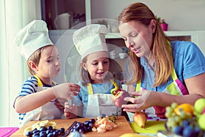 Cute kids with mother preparing a healthy fruit snack in kitchen