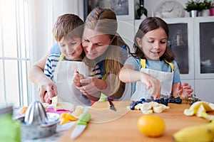 Cute kids with mother preparing a healthy fruit snack in kitchen