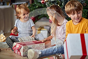 Cute kids opening  Christmas gift at home