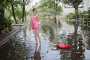 Cute kids playing with paper boat in the puddles after warm summer rain, happy childhood