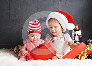 Cute kids on rug opening a Christmas present