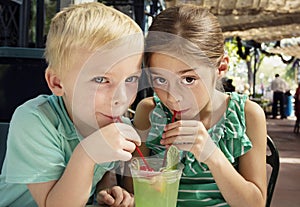 Cute kids sharing a mint julep drink at a cafe photo