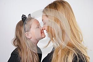 Cute kind caucasian blonde mom and daughter posing on white background. a parent and a child experience love and hug.