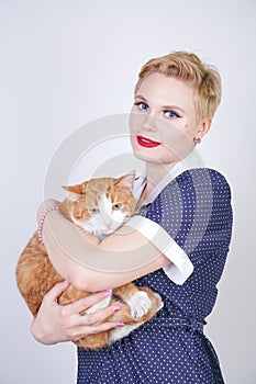 Cute kind woman with short hair in pinup polka dot dress holding her beloved pet on a white background in the Studio. plus size ad