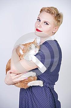 Cute kind woman with short hair in pinup polka dot dress holding her beloved pet on a white background in the Studio. plus size ad