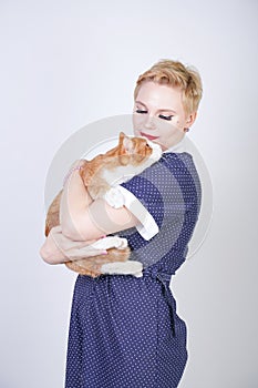 Cute kind woman with short hair in pinup polka dot dress holding her beloved pet on a white background in the Studio. plus size ad