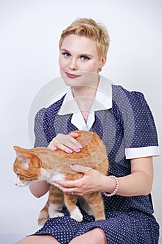 Cute kind woman with short hair in pinup polka dot dress holding her beloved pet on a white background in the Studio. plus size ad