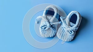 Cute knitted baby booties on blue background with copy space
