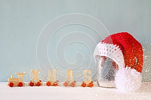 cute knitted santa hat on mason jar with christmas tree photo