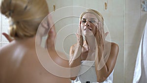 Cute lady applies face moisturizer on dry sensitive skin, cosmetology at home