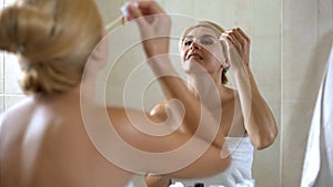Cute lady applies face moisturizer on dry sensitive skin, cosmetology at home