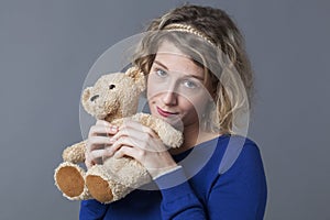 Cute lady holding up her cuddly toy remembering